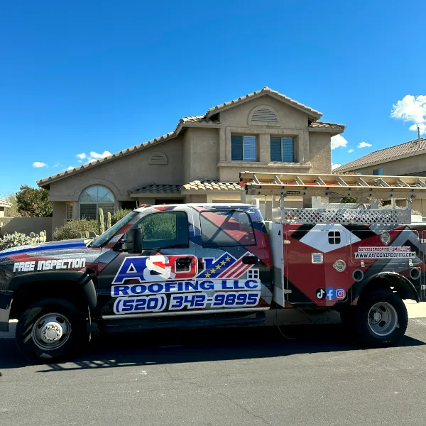 Branded work truck parked in front of a suburban home, wrapped with A And D Roofing graphics, contact number, and ladder racks, advertising a local roofing company in Tucson, AZ.