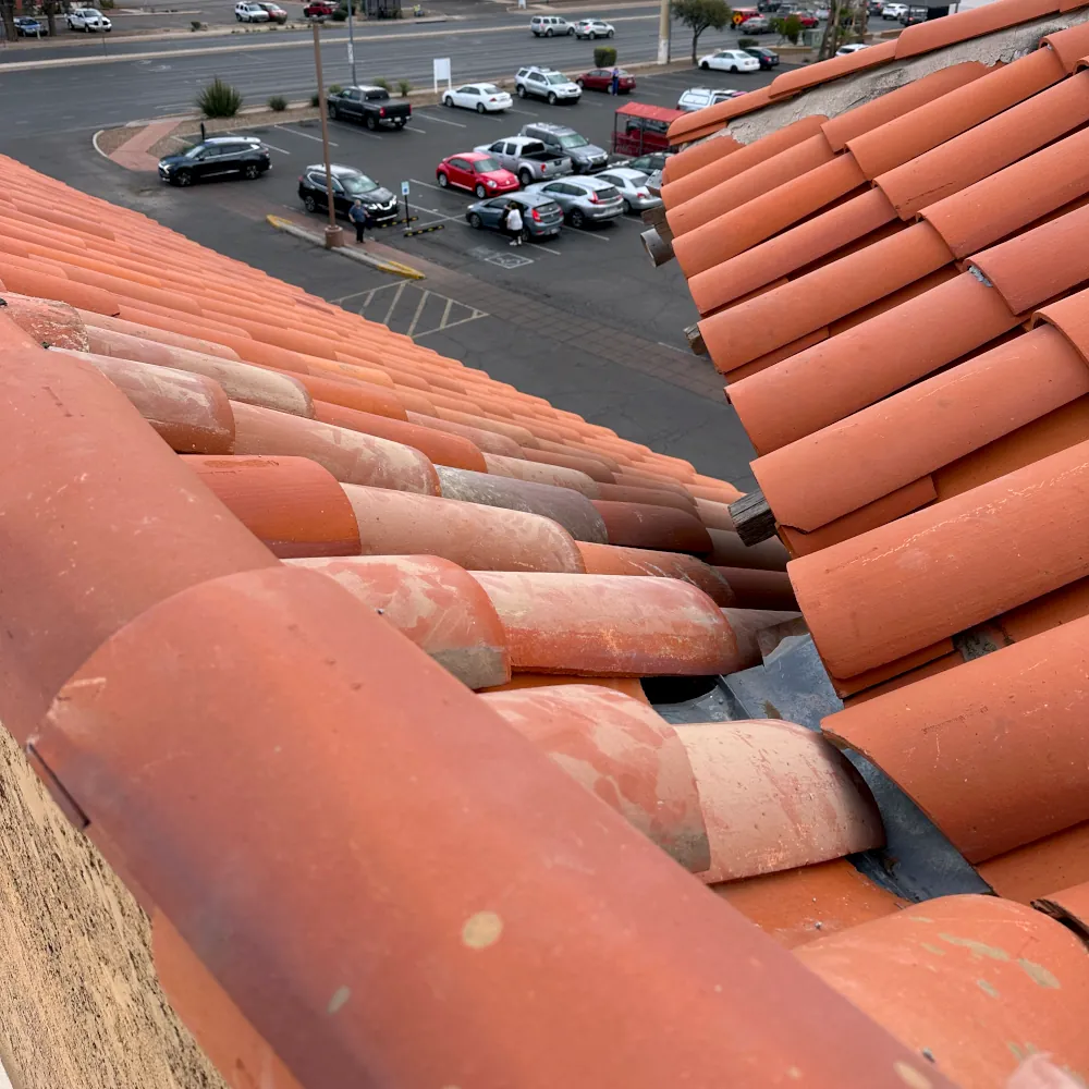 A new tile roof installation in Tucson with a close-up view of terracotta tiles on a roof with parking lot below.